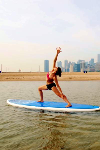 Donna che fa stretching sulla tavola da paddle sul lago