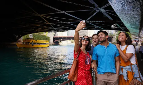Persone in posa per una foto lungo il fiume sotto un ponte 