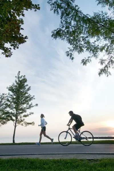 Persona che corre e persona che va in bicicletta lungo la pista ciclabile del lungolago di Chicago