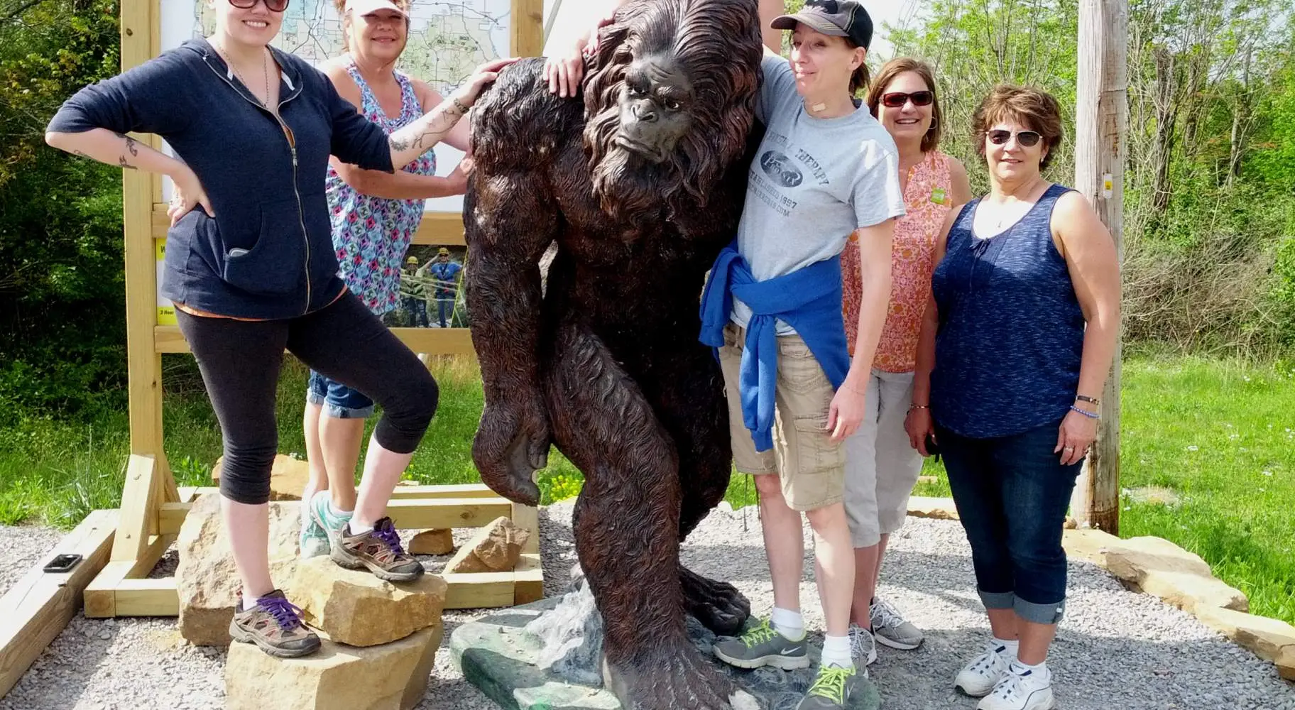 Un gruppo di sei donne in posa con la statua di un sasquatch di nome Sassy