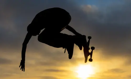 Uno skateboarder salta in aria contro il sole al tramonto in uno skate park di Chicago.
