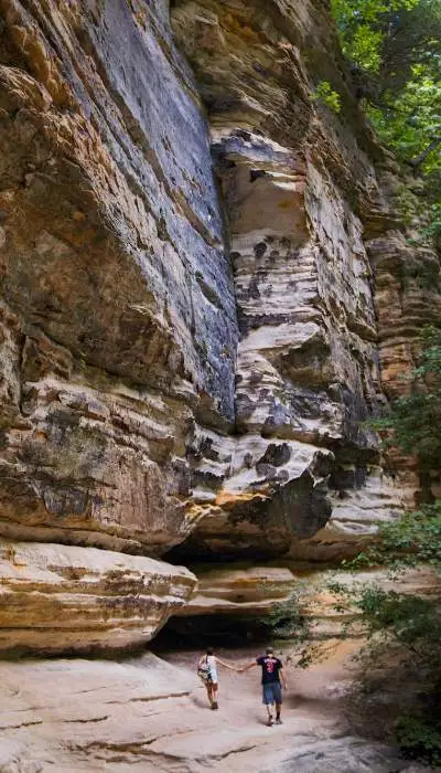 Una coppia che cammina accanto a una roccia imponente