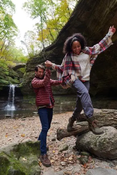 Due persone che si arrampicano sulle rocce davanti a una cascata di roccia