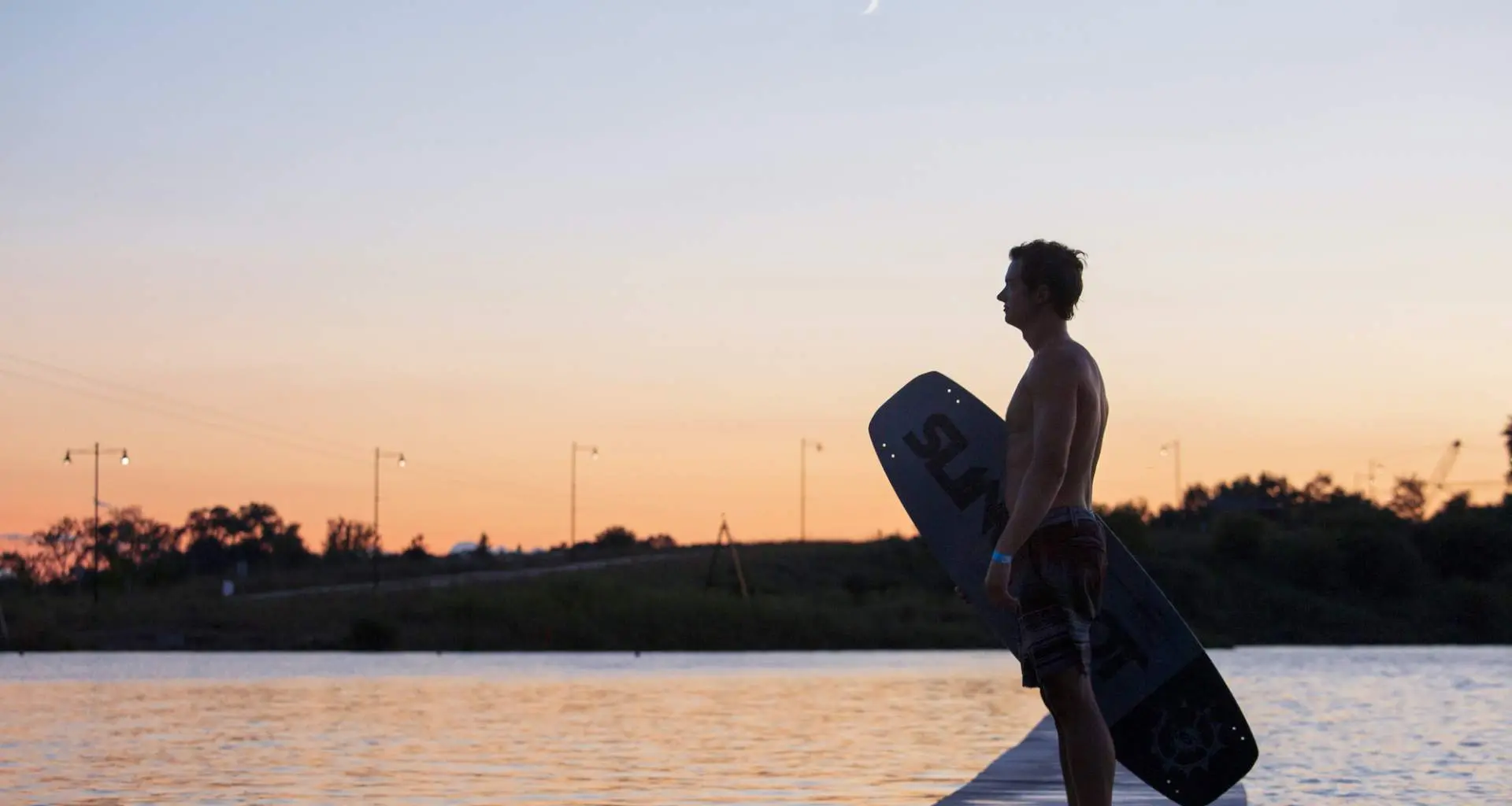 Wakeboarder in piedi accanto al Quarry Cable Park al tramonto