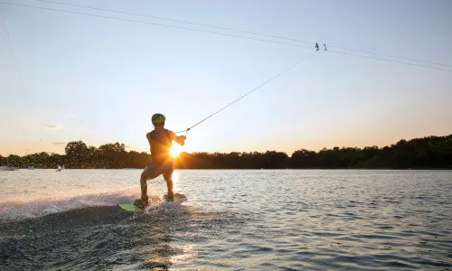 Una persona che fa wakeboarding al tramonto 