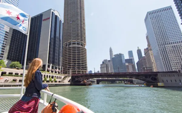 Una donna si appoggia al parapetto di un battello da crociera sul fiume Chicago, osservando gli edifici della città.