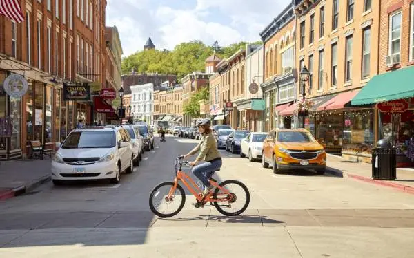 Un ciclista su una e-bike attraversa la strada principale di una piccola città