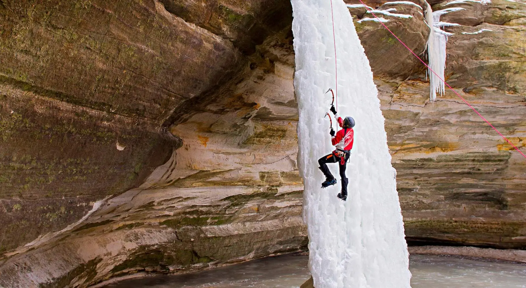 Persona che si arrampica su una cascata di ghiaccio