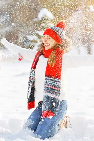 Una madre con il suo bambino, vestita in modo caldo per il tempo, che lancia la neve in aria