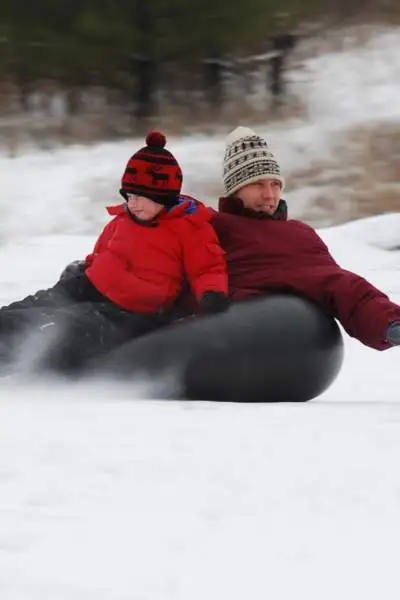 Un uomo e un ragazzo che fanno snowtubing sul Monte Hoy