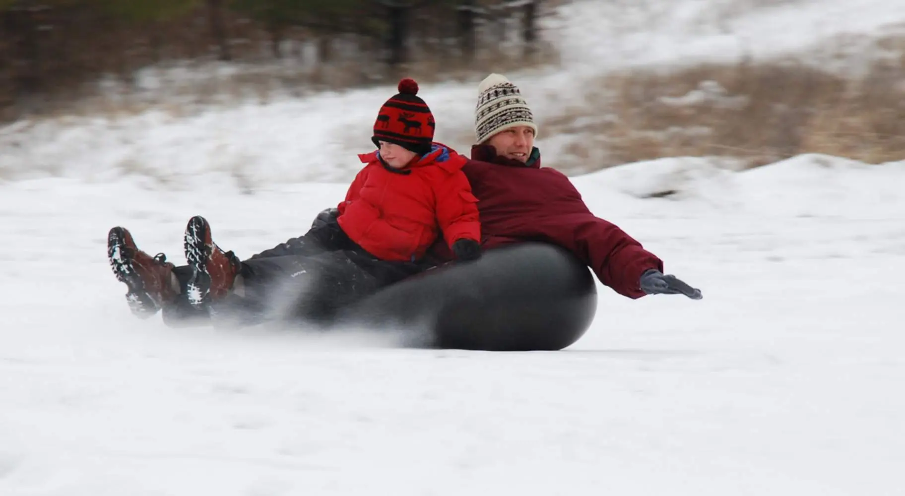 Un uomo e un ragazzo che fanno snow tubing sul Mount Hoy
