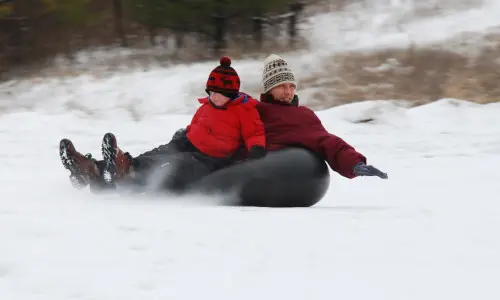 Un uomo e un ragazzo che fanno snowtubing sul Monte Hoy