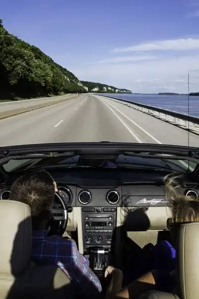 Due persone che guidano in un'auto senza tetto lungo una strada