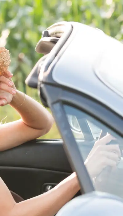 Ragazze in una decappottabile che passano accanto a campi di grano.