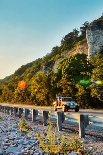 L'alba che splende sull'acqua e un'auto che percorre la strada accanto ad essa