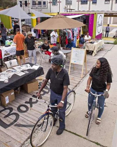 Due persone in bicicletta davanti a un mercato all'aperto