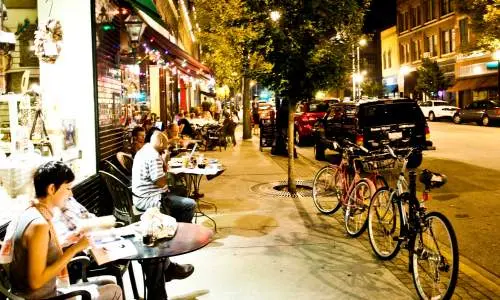 Persone che leggono e mangiano fuori dai negozi lungo la strada