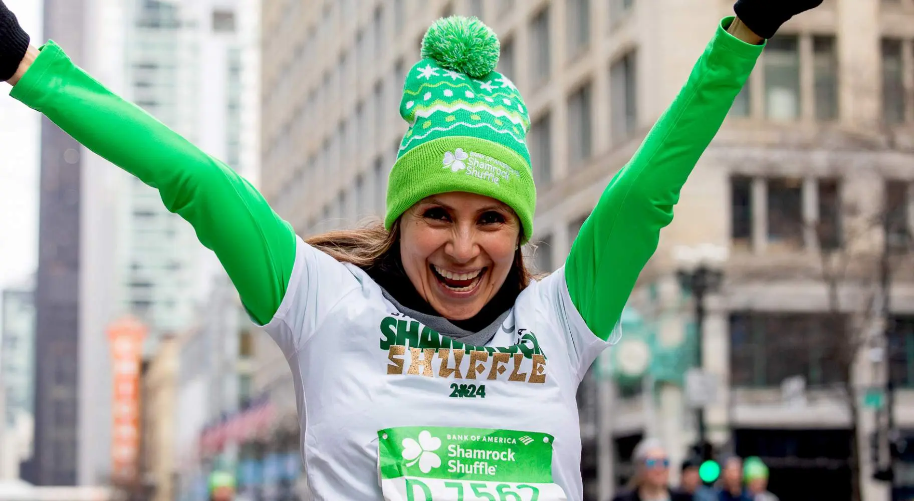 Una partecipante a una corsa podistica in verde con le braccia alzate in aria